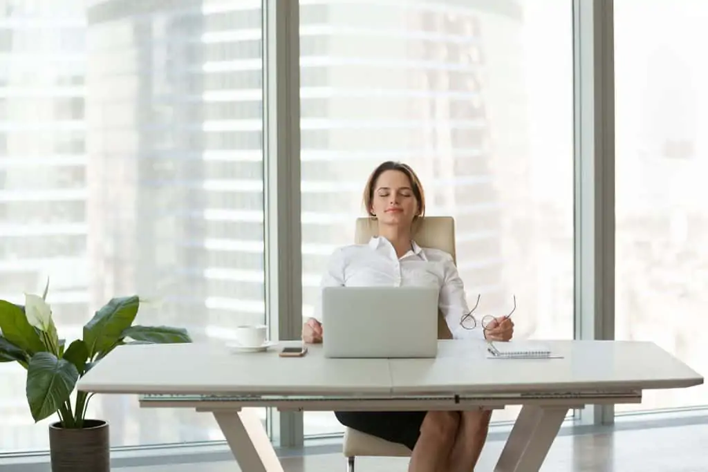 business woman sitting at desk with eyes closed