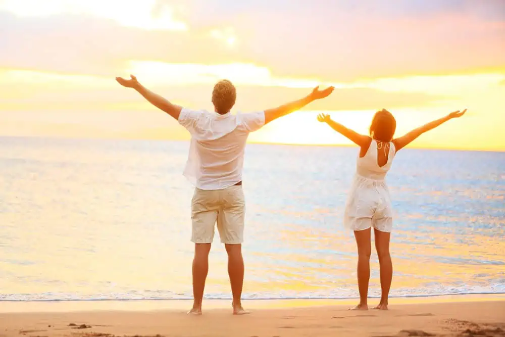 Happy cheering couple enjoying sunset at beach — Photo